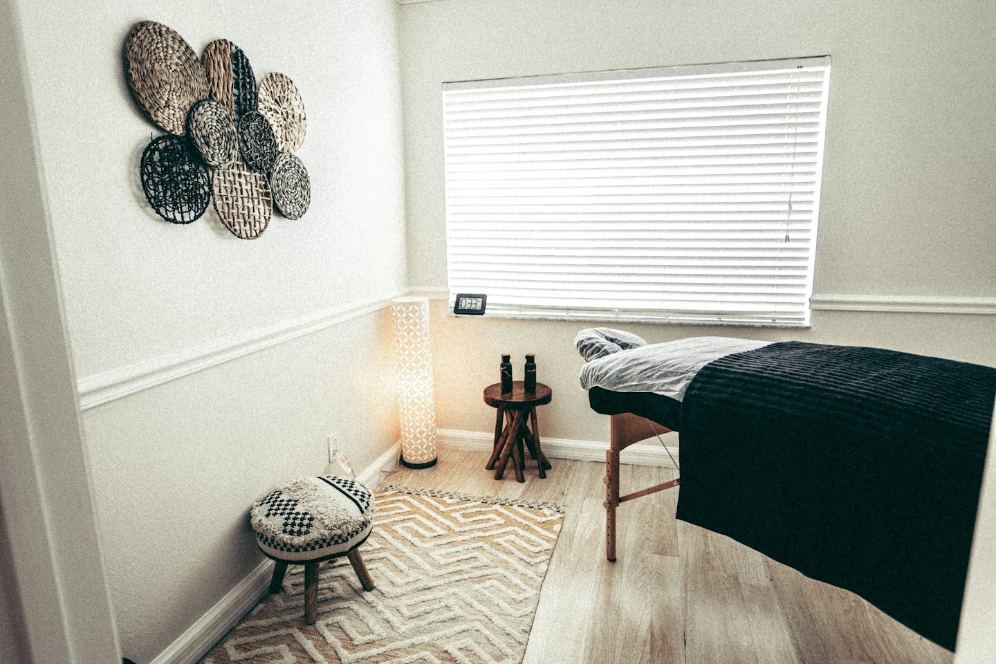 Cama de masajes vacía en una sala de terapia tranquila con suelo de madera.