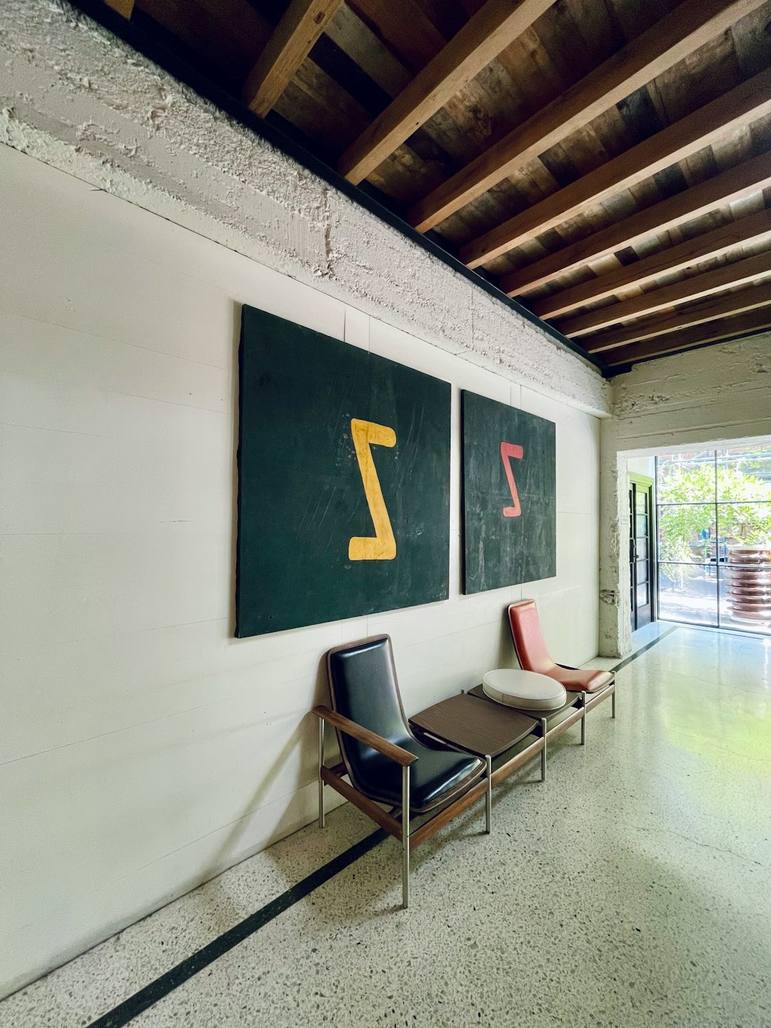 Sala de espera con sillas y arte abstracto en una oficina moderna.